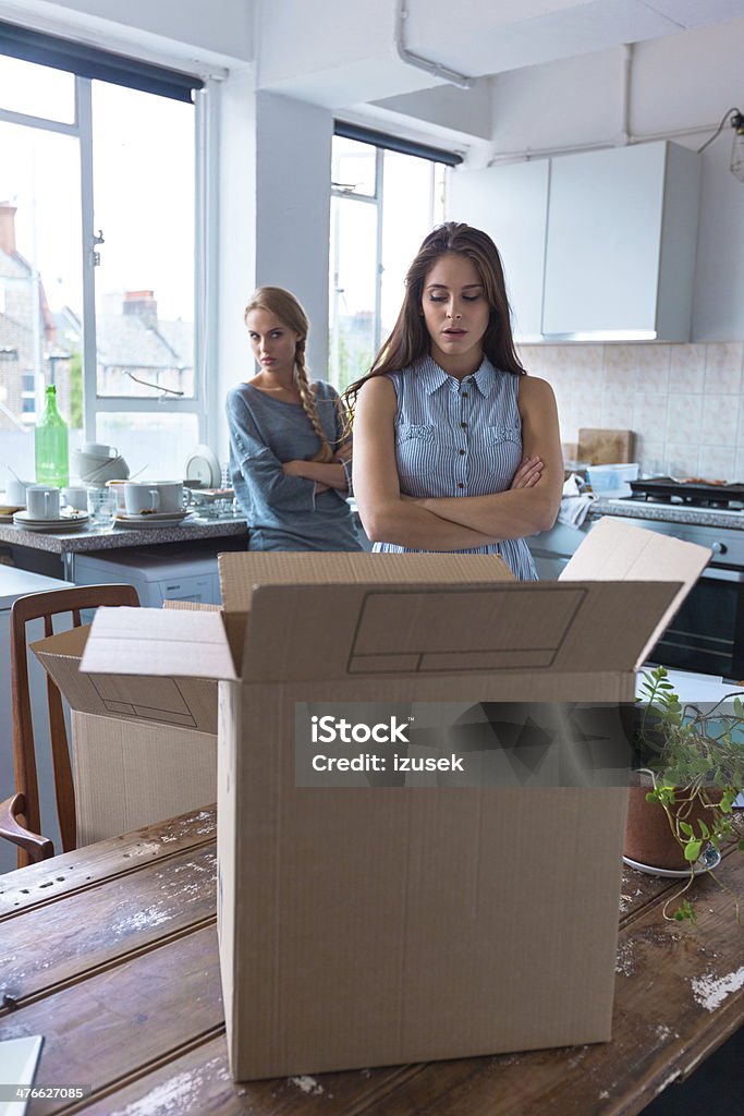 Conflict between roommates Two girls having quarrel at home. Cardboard box in the foreground. Arguing Stock Photo