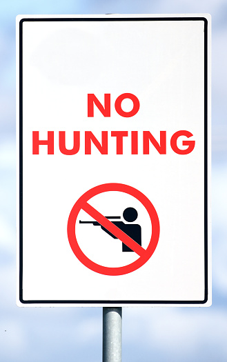 A sign showing the prohibition of Hunting in this area, no shooting stop sign posted.