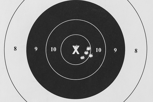 Five bullet holes inside the ten ring on a small bore bull's-eye paper target