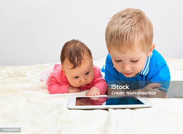 Brother And Sister With Touch Pad At Home Stock Photo - Download Image Now - Baby - Human Age, Baby Girls, Bed - Furniture