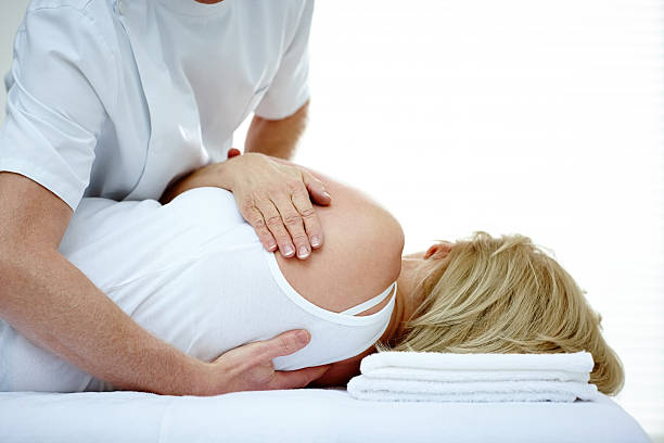Male osteopath treating back problem of a woman Male osteopath treating back problem of a woman lying on medical room osteopath photos stock pictures, royalty-free photos & images