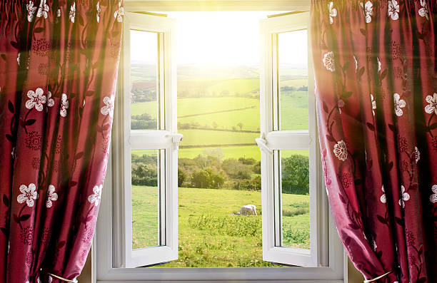 Open window with countryside view and sunlight streaming in stock photo