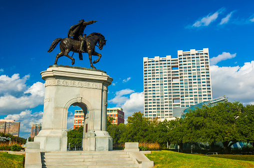 Houston, United States - December 1, 2012: A scene in the Museum Square district of Houston, featuring the Sam Houston monument and arch on the left side, and various residential high-rise buildings in the background.