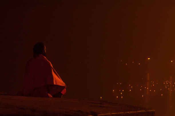 indiano sadhu meditar no rio ganges sagrado à noite - sadhu imagens e fotografias de stock