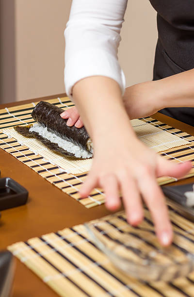 istock Woman hand moistening with water a sushi roll edge 476662971