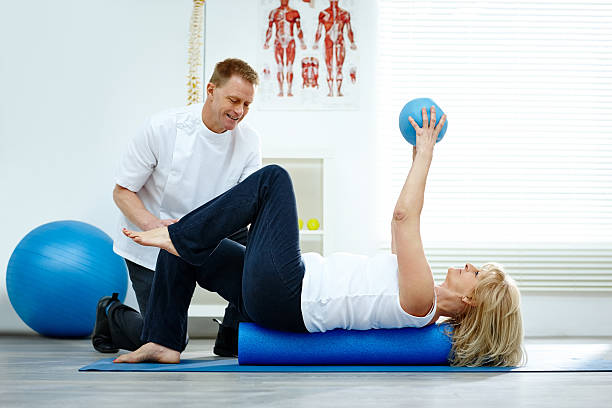 terapeuta ajudando seu paciente com exercícios de pilates - stretching chiropractor alternative medicine human muscle - fotografias e filmes do acervo