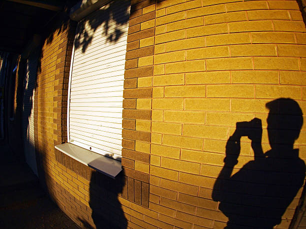The shadow of a man with a camera in hand, who photographed a brightly lit wall with wide angle fisheye lens and distortion view