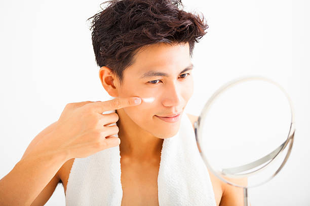 istock smiling man applying cream lotion on face 476671878
