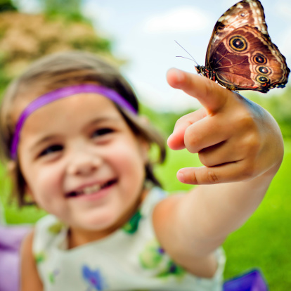 Girl with butterfly outdoors in summer