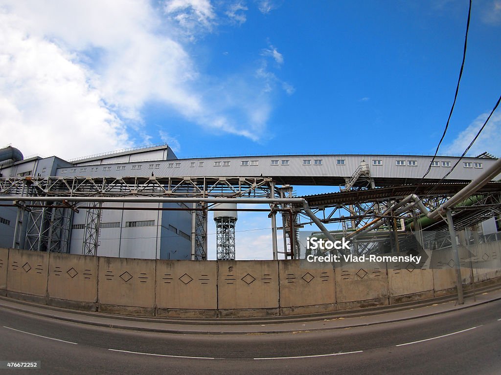 Industrial buildings behind a fence facing the road Industrial buildings behind a fence facing the road with wide angle distortion view 2015 Stock Photo