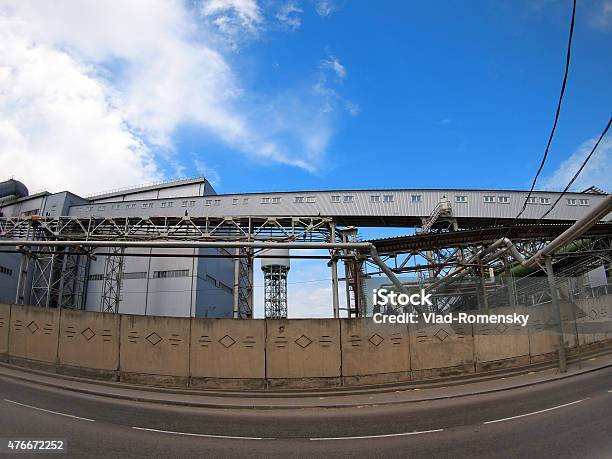 Industrial Buildings Behind A Fence Facing The Road Stock Photo - Download Image Now