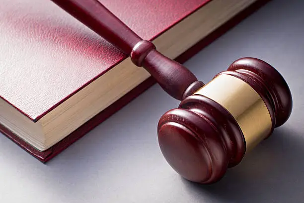 Photo of Wooden Gavel Resting on Red Leather Book