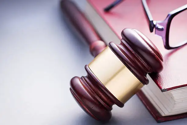 Photo of Wooden Gavel Resting on Red Leather Book