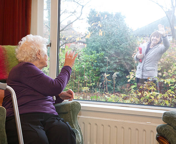 独立したリビングエリア、高齢者お客様の手を振るに別れを告げたプロフェッショナル carer ます。 - waving separation bye women ストックフォトと画像