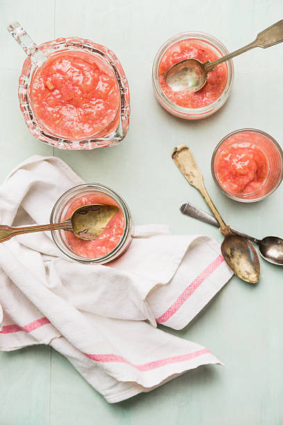 Rhubarb compote in glass and cup with spoons, top view Rhubarb compote in glass and cup with spoons, top view compote stock pictures, royalty-free photos & images