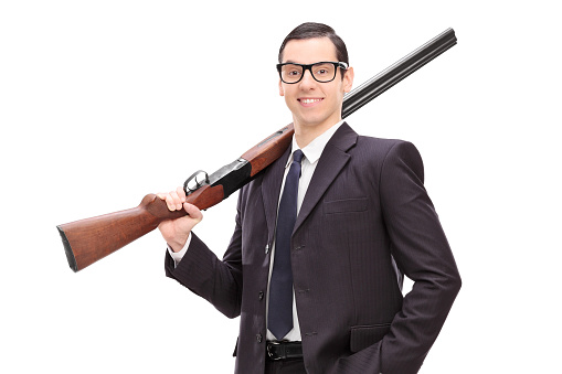 Businessman holding a rifle over his shoulder isolated on white background