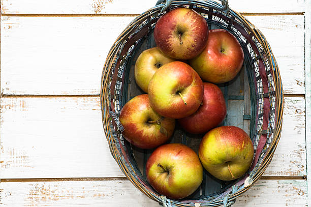 istock Red apples in basket on white wooden background 476685276