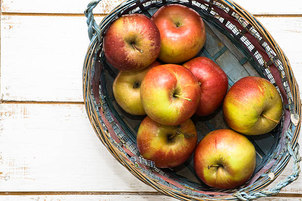 istock Red apples in basket on white wooden background 476685284