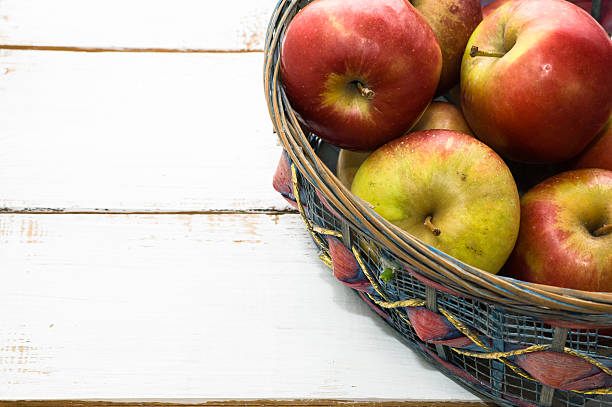 istock Red apples in basket on white wooden background 476685286