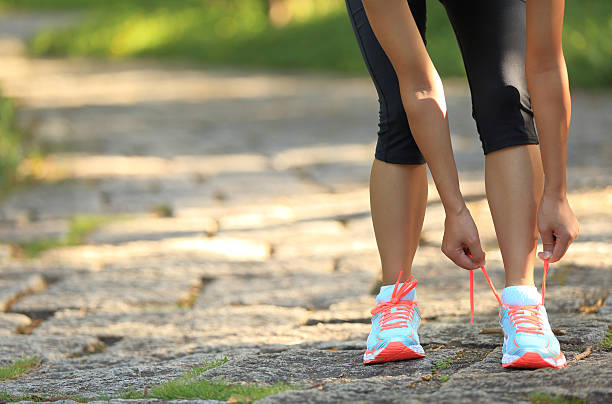 istock young woman runner tying shoelaces on stone trail 476685890