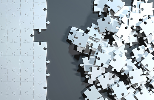 Partially assembled puzzle with white jigsaw pieces, while others are still messy and unordered. One side of the image shows part of a completed puzzle, while the other shows the work in progress on a dark gray background. Finding a solution to a problem and choosing the right strategy to solve disorganization to complete a project by putting together the puzzle. Digital generated image, view from top.