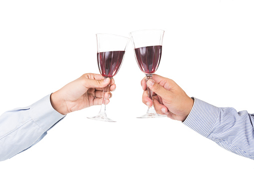 Hands in long sleeve shirt toasting red wine in crystal glasses