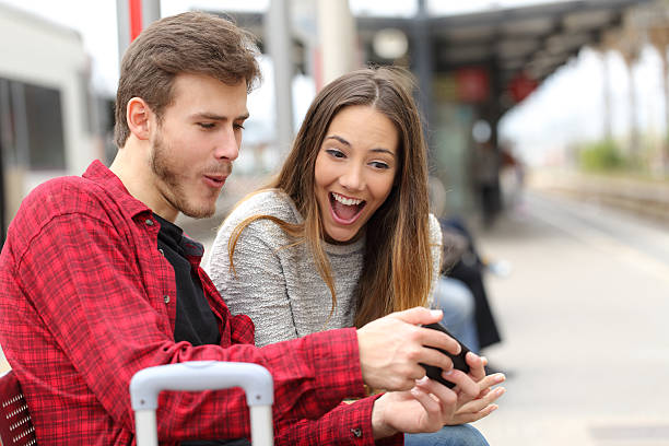 istock Couple playing games with a smart phone in train station 476702398