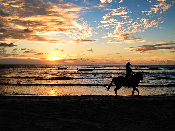 istock woman riding on the beach at sunset. 476703640