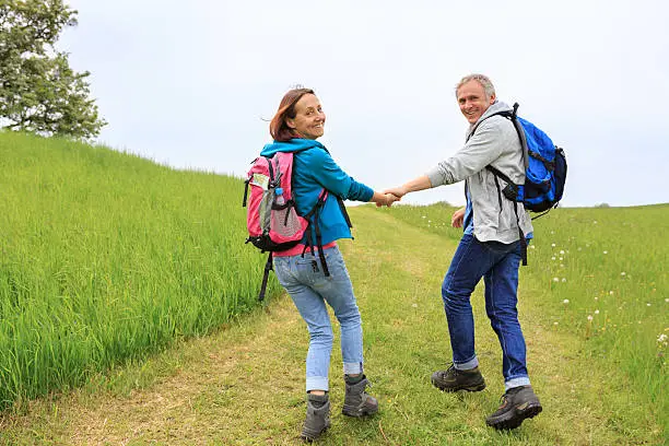 Mature couple with backpack hiking in the green nature