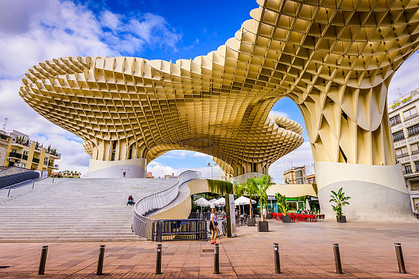 Metropol Parasol (by architect Jurgen Mayer H) in Seville Seville, Spain - November 7, 2014: A Pedestrian passes the Metropol Parasol (by architect Jurgen Mayer H). Located in the old quarter, the structure opened to public controversy in 2011. sevilla province stock pictures, royalty-free photos & images