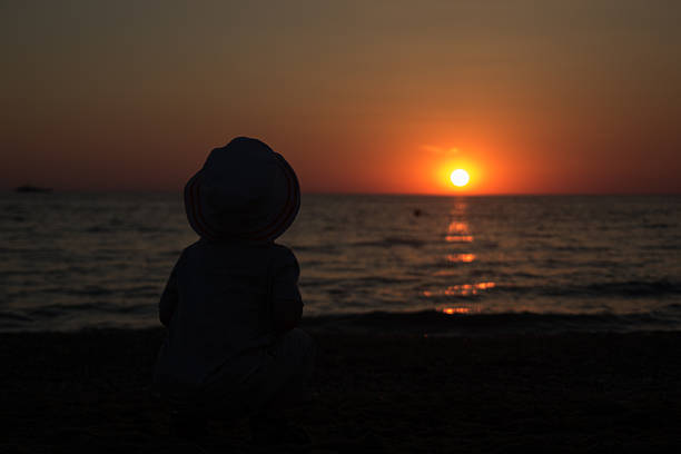 istock child sitting  on the beach and enjoy the sunset 476708918