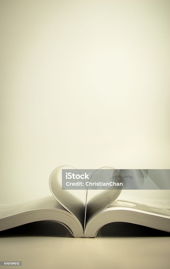 Opened book with heart page Opened book with heart page against blank background. Poetry - Literature Stock Photo