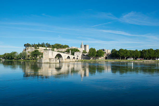 Pont d'Avignon and Rhone River in Avignon, France View of the Pont Saint-Bénézet, also called the Pont d'Avignon, on a beautiful summer day on the Rhone River in Avignon, France. The bridge, first constructed in the 12th century, was costly to maintain and so was abandoned in the mid-17th century. The four surviving arches are believed to have been built in around 1345 by Pope Clement VI during the Avignon Papacy. avignon france stock pictures, royalty-free photos & images