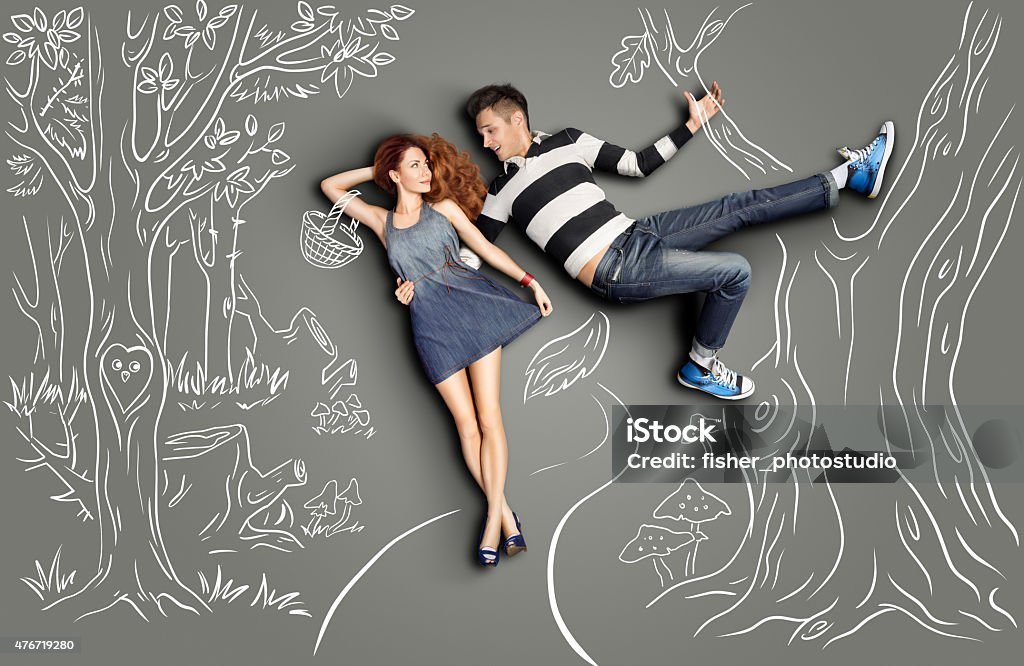 Date in woods. Happy valentines love story concept of a romantic couple walking in the wood and flirting against chalk drawings nature background. Male as a Big Bad Wolf hanging on a tree and hugging his girlfriend as a Little Red Riding Hood. Boyfriend Stock Photo