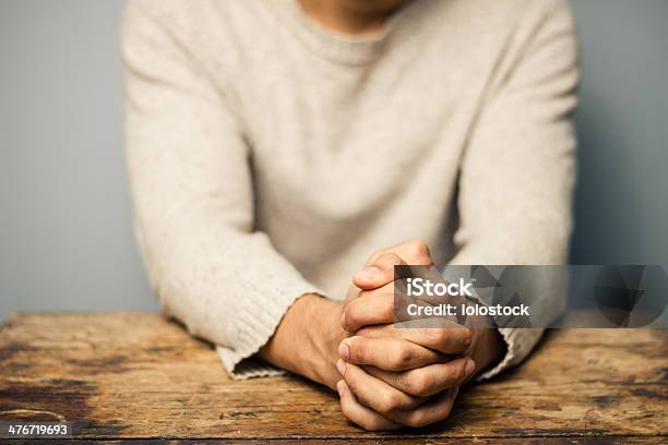 Rezar Hombre En Escritorio Foto de stock y más banco de imágenes de Adulto joven - Adulto joven, Enfoque diferencial, Enfoque en primer plano