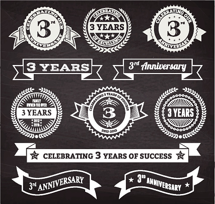 three year anniversary hand-drawn chalkboard royalty free vector background. This image depicts a black chalkboard with multiple anniversary announcement designs. There is chalk dust remaining on the chalkboard and the chalkboard texture serves a perfect backdrop for making the anniversary announcements look authentic and elegant.