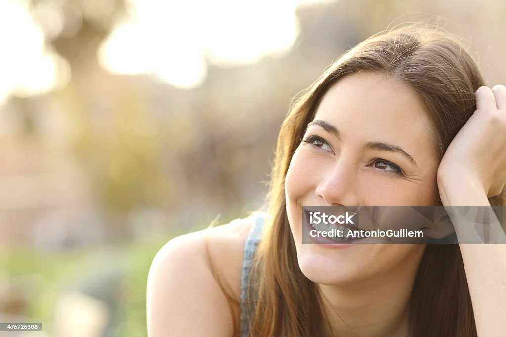 Woman with white teeth thinking and looking sideways Woman with white teeth thinking and looking sideways in a park in summer Women Stock Photo