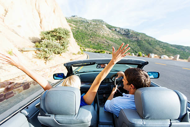 istock Happy Woman Enjoying Road Trip While Man Driving Convertible 476728797