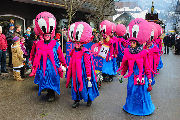 Carnival parade in Germany with spectacularly beautiful costums Bad Hindelang, Germany - Februar 15, 2015: Unknown persons participate at the annual public carnival parade through the streets of city Bad Hindelang in southern part of Bavaria. The actors are disguised as in hand made costum with big hat, styled as pink head of an octopus with big eyes. mardi gras body painting stock pictures, royalty-free photos & images
