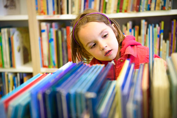 istock Little girl is choosing a book in the library 476738980