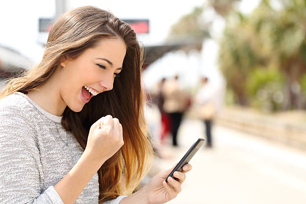 istock Euphoric woman watching her smart phone in a train station 476739206