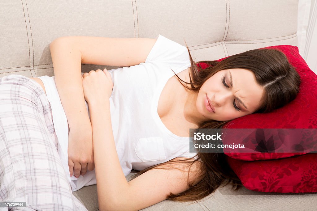 Period pain Young woman in the sofa with period pain 2015 Stock Photo