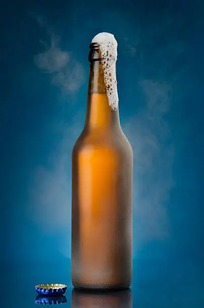 Photo of Beer frothing out of brown bottle