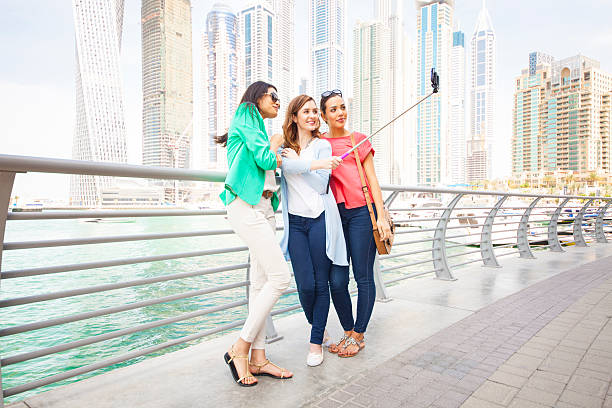 istock Smiling women taking selfie against cityscape 476747134