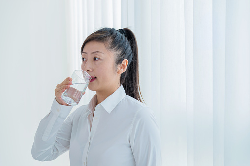 Beautiful woman drinking a glass of water at home.
