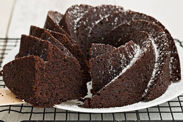 Serving A Slice Of Cake A high angle close up of a slice of chocolate bundt cake on a plastic spatula. sprinkling powdered sugar stock pictures, royalty-free photos & images