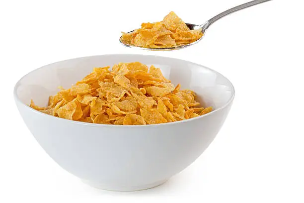 bowl of cornflakes with a spoon on white background