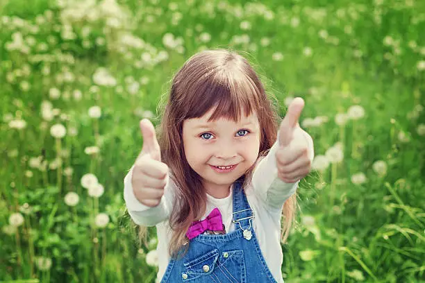 Photo of cute child girl or kid with thumbs up shows class