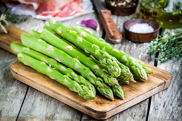 Fresh organic asparagus on a cutting board with Parma ham Fresh organic asparagus on a cutting board with Parma ham on a rustic table asparagus photos stock pictures, royalty-free photos & images