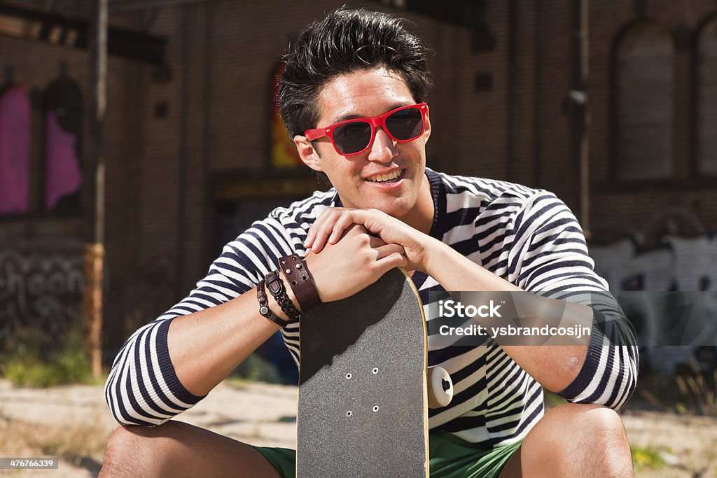 Urbana homem asiático com vermelho e óculos de sol e andar de skate. - Foto de stock de Adulto royalty-free